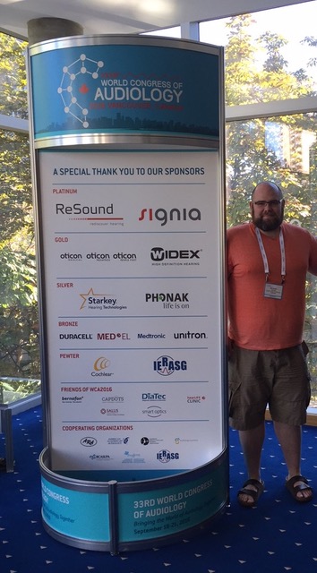 Michael standing beside a listing of the sponsors
